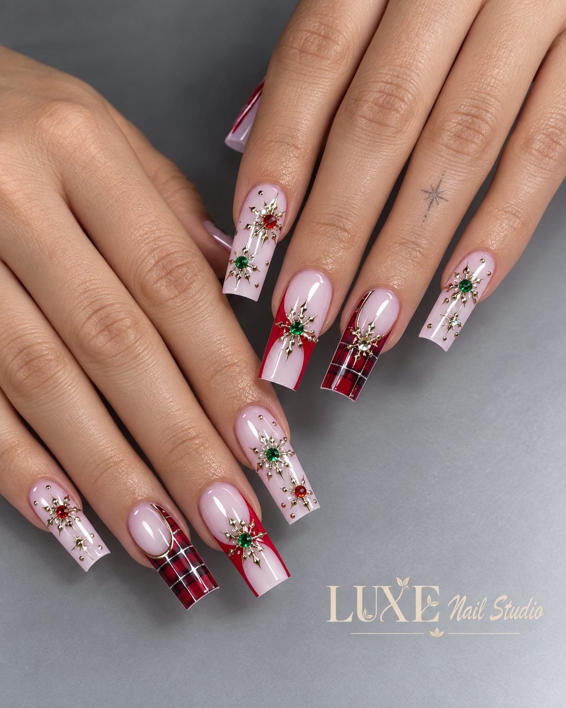 Pink coffin nails with gold stars, red plaid tips, and green gems by Luxe Nail Studio