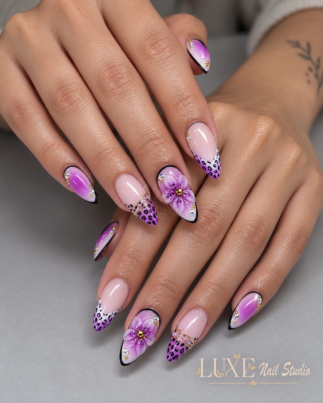 Lilac almond nails with leopard tips, purple flowers, and crystals by Luxe Nail Studio
